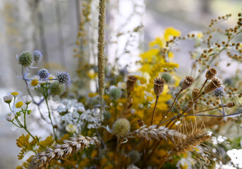Floral summer or autumn background. A bouquet of wild flowers in a vase on the windowsill. Sunny day, blurred background. Shallow depth of field, soft focus.