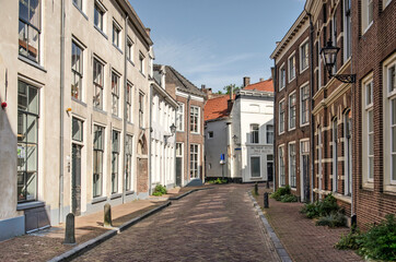 Fototapeta na wymiar Zwolle, The Netherlands, August 9, 2021: street in the old town with traditional houses and brick and plaster facades.