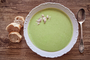 Broccoli puree soup with slices of bread on a wooden table