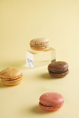 Several creamy and chocolate macaron pastry scattered on beige colored surface
