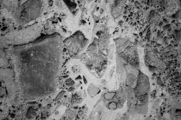 evocative black and white image of very porous concrete wall