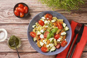 Italian pasta fusilli tricolore with cherry tomatoes, zucchini and feta cheese in a blue shallow...
