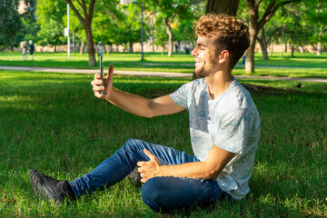 man sitting in the park with phone in hand recording a tiktok