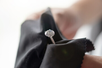 Jeweller cleaning jewelry diamond ring with fabric cloth