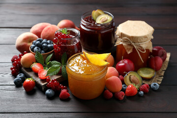 Jars with different jams and fresh fruits on wooden table