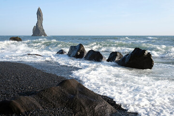 Waves coming in at Reynisfjara Black Beach, Iceland, with rock formations in the background