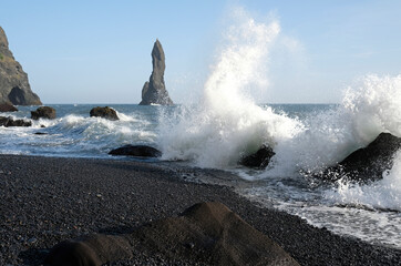 Waves coming in at Reynisfjara Black Beach, Iceland, with rock formations in the background
