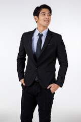 Obraz na płótnie Canvas Portrait shot of Asian young black short hair smart confident businessman entrepreneur in formal suit with necktie standing smiling hold hands in pockets look at camera in front of white background