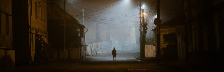 Lonely woman walking in a foggy old city in city street lights