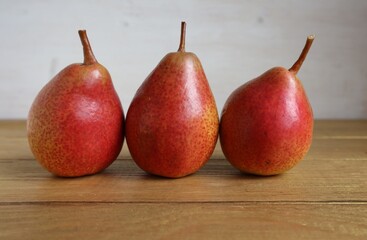 Red ripe pears lie on a brown wooden surface.