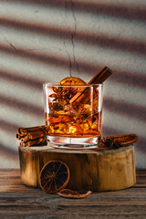 Cocktail with brandy and orange liquor, cinnamon and star anise on wooden block