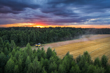 
Combine harvesting crop field at colorful sunset colors. Harvest time in farm at stormy weather and dark clouds.
