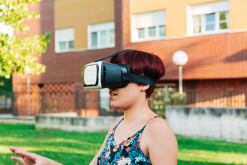 Young woman with virtual reality glasses in a city field. digitization and metaverse  concept