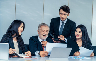 Senior caucasian manager working in office with assistance of young Asian business people and...
