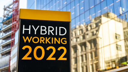 Hybrid Working 2022 on a city-center sign in front of a modern office building