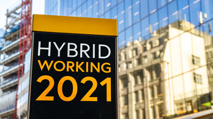 Hybrid Working 2021 on a city-center sign in front of a modern office building