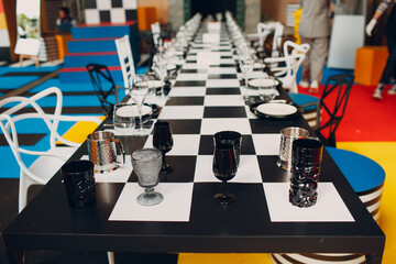 Wedding table decor like a chessboard with black and white dishes glasses.