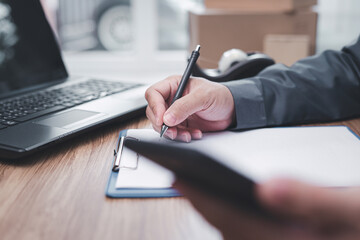 A man check order or list inventory in stock in write on document and check data online in smartphone : Online order concept