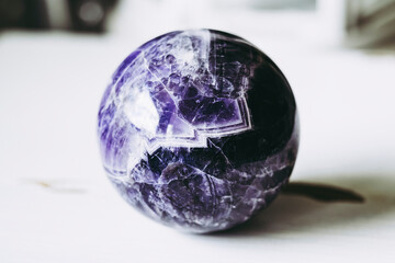 Boule de divination en améthyste à chevrons sur un fond blanc - Minéral naturel