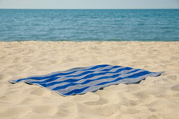 Striped beach towel on sand near sea