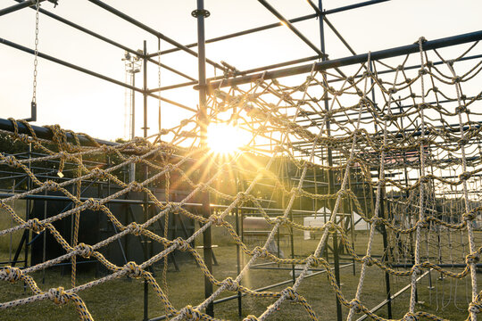 obstacle course races climbing rope net with sunset sky - Powered by Adobe