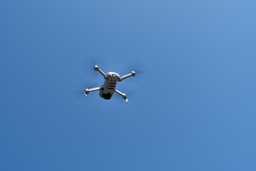 A small flying drone with camera in a blue sky