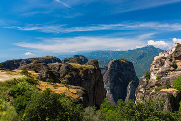 Fototapeta na wymiar ギリシャ　メテオラの断崖絶壁の岩山の上に建つヴァルラアム修道院と奇岩群と後ろに見えるピンドス山脈