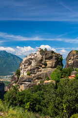 Fototapeta na wymiar ギリシャ　メテオラの断崖絶壁の岩山の上に建つヴァルラアム修道院と奇岩群と後ろに見えるピンドス山脈