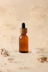 Cosmetic bottle with flowers on pastel beige background. Close up