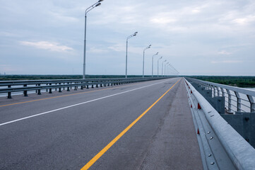 Fototapeta na wymiar An empty road bridge over the river with lanterns in summer