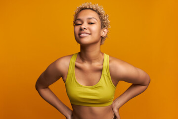 Good-looking self-confident blonde African female with flirting face expression, dressed in yellow...