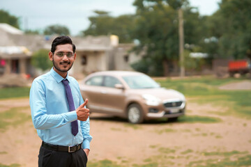 Young indian banker or financier standing with car