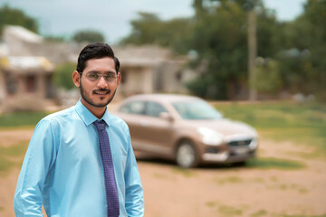 Young indian banker or financier standing with car