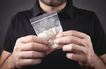 Drug dealer holding plastic packet cocaine.