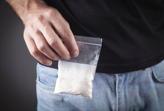 Drug dealer holding plastic packet cocaine.