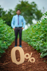 Young indian agronomist or financier showing zero percent sign or symbol at agriculture field