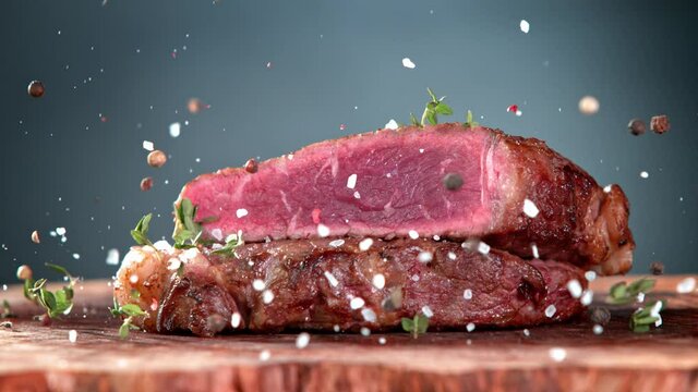 Super Slow Motion Shot of Seasoning Falling on Grilled Beef Meat Slice on Wooden Board at 1000fps.