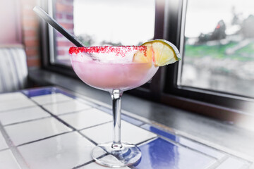 Margarita alcoholic cocktail with tequila and a pile of lemon in a glass with edges sprinkled with...