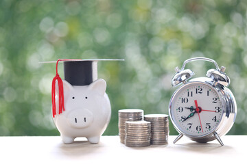 Graduation hat on piggy bank with stack of coins money on natural green background, Saving money for education concept