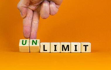 Limit or unlimit symbol. Businessman turns cubes, changes words 'limit' to 'unlimit'. Beautiful orange table, orange background, copy space. Business, limit or unlimit concept.
