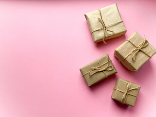 A gift box wrapped in kraft paper on a pink background. View from above, flat lay, top view design. Minimalism. Concept sales, shopping, christmas holidays and birthday.