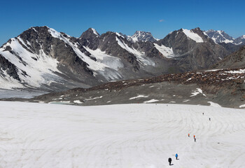 A tourist group of hikers is walking in a chain along the glacier in the Tien Shan mountains....