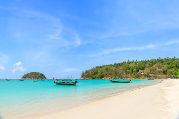 Kata Beach with crystal clear water and wooden traditional boat, famous tourist destination and...