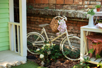 Fototapeta na wymiar Decorative white vintage bicycle against brick wall. Old bicycle parked against a stone wall in garden. Street decoration backyard. Autumn garden corner. Patio of house with garden plants and bicycle.