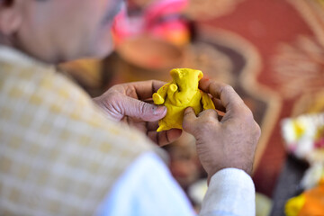 An indian priest making lord ganesha from flour mixed with tumeric & ghee