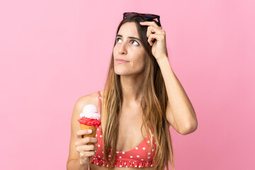 Young caucasian woman holding an ice cream isolated on pink background having doubts and with confuse face expression