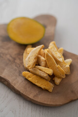 Freeze-dried mango with fresh one on olive wood board
