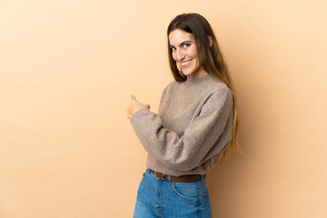 Young caucasian woman over isolated background pointing back