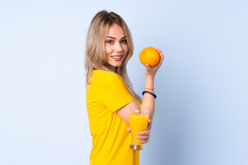 Teenager Russian girl holding an orange isolated on blue background