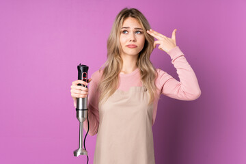 Teenager Russian girl using hand blender isolated on purple background with problems making suicide gesture